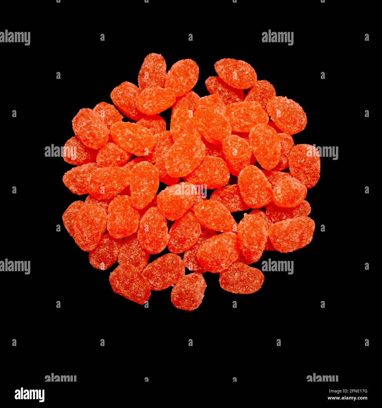 caramelle caramelle caramelle caramelle in una gelatina rivestita di zucchero arancio brillante cumulo rotondo mucchio sulla superficie nera della cucina Foto Stock