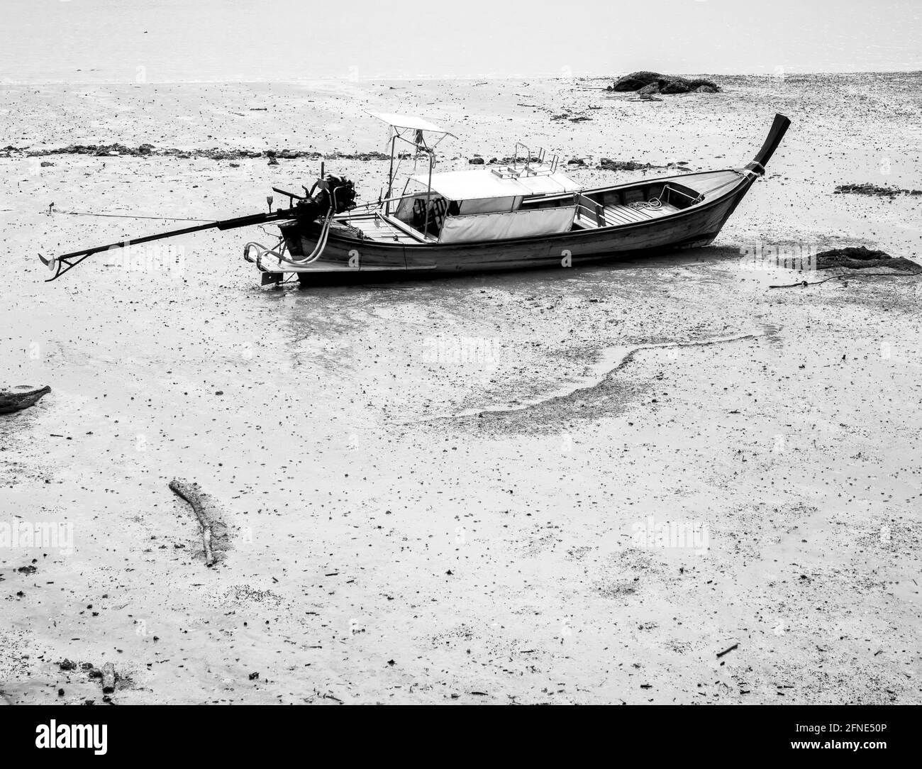 Barca a coda lunga vuota di pesca del villaggio nel fango della spiaggia in stile bianco e nero con spazio per la copia. Stile di vita dei pescatori thailandesi. Foto Stock