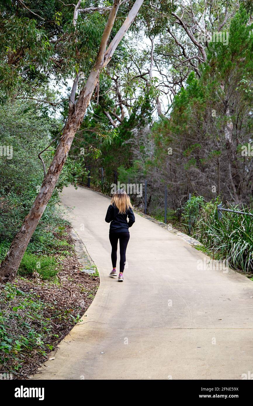 Una donna che cammina nel Kings Park sulla Law Walk percorso attraverso la macchia nativa Foto Stock