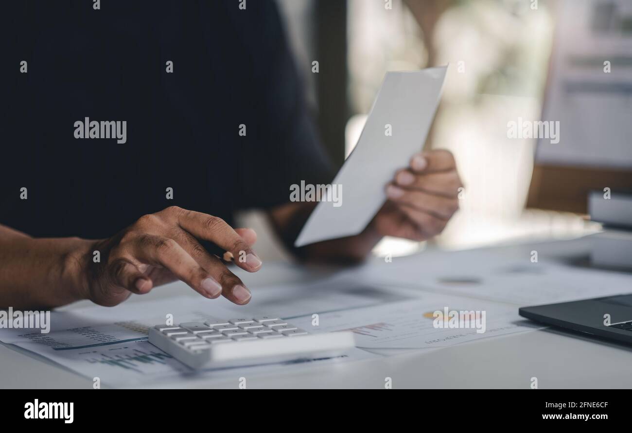 Primo piano uomo contabilità fatture e pagamenti con calcolatrice a casa. Foto Stock