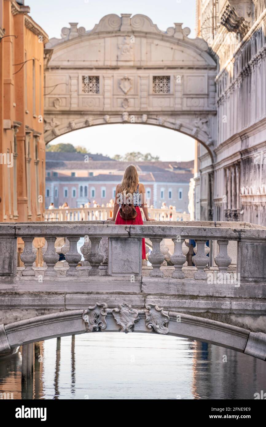 Giovane donna con gonna rossa, turista appoggiato su ringhiera ponte, ponte sul Rio di Palazzo, dietro Ponte dei Sospiri, Venezia, Veneto, Italia Foto Stock