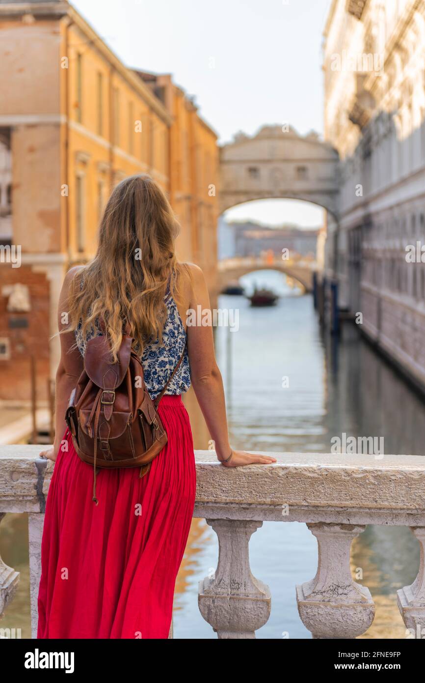 Giovane donna con gonna rossa, turistica su un ponte sul Rio di Palazzo, dietro Ponte dei Sospiri, Venezia, Veneto, Italia Foto Stock