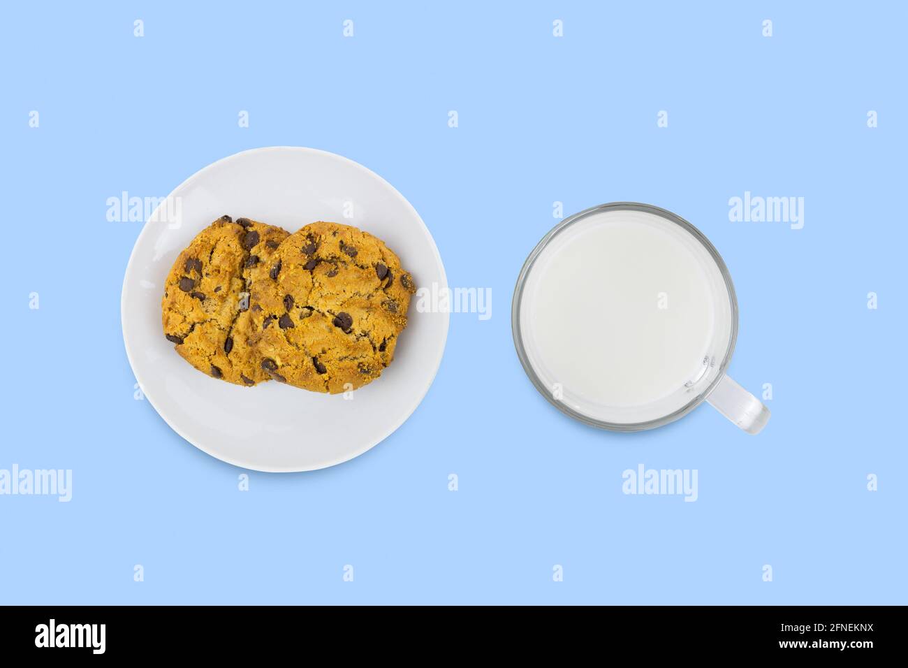 Due biscotti americani su piatto di porcellana bianca e una tazza di latte trasparente su superficie blu. Vista dall'alto. Foto Stock