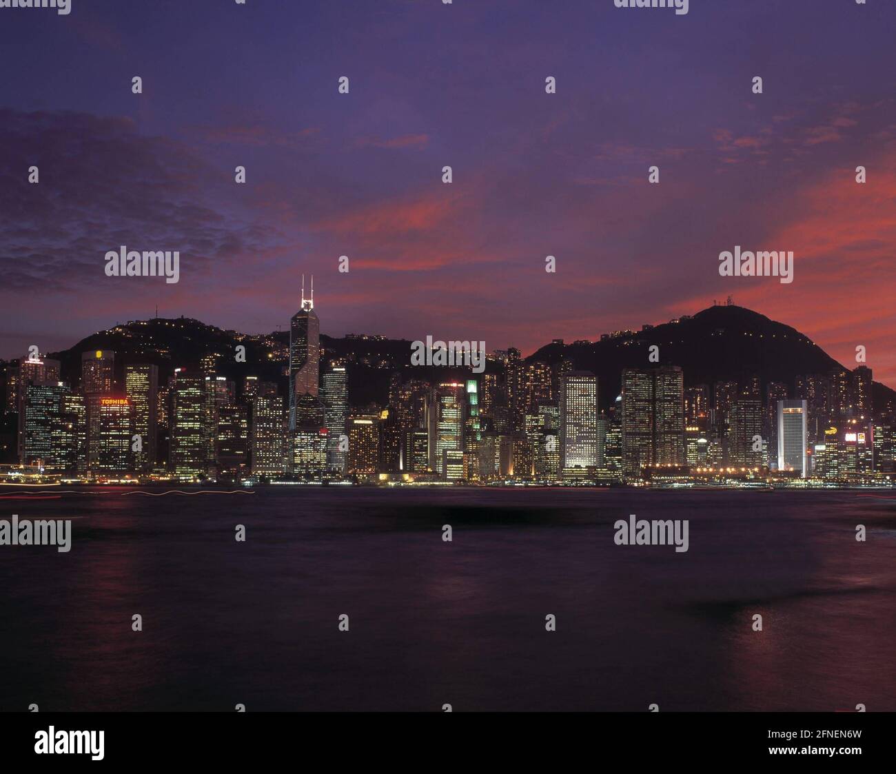 Foto notturna dello skyline di Victoria luminoso con il grattacielo Bank of China (m.) e la montagna Victoria Peak sullo sfondo (r.). [traduzione automatizzata] Foto Stock