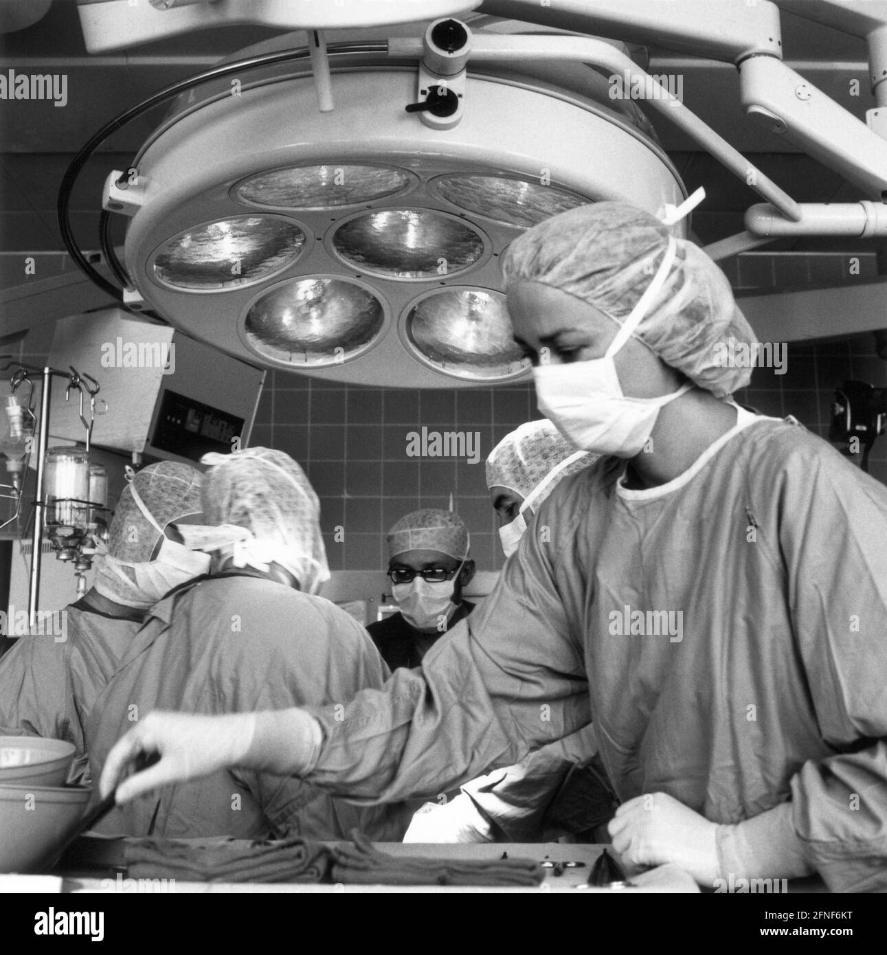 Infermiere del teatro operatorio al lavoro nella sala operatoria del dipartimento di chirurgia vascolare, Norimberga South Hospital. In background l'équipe medica. [traduzione automatizzata] Foto Stock