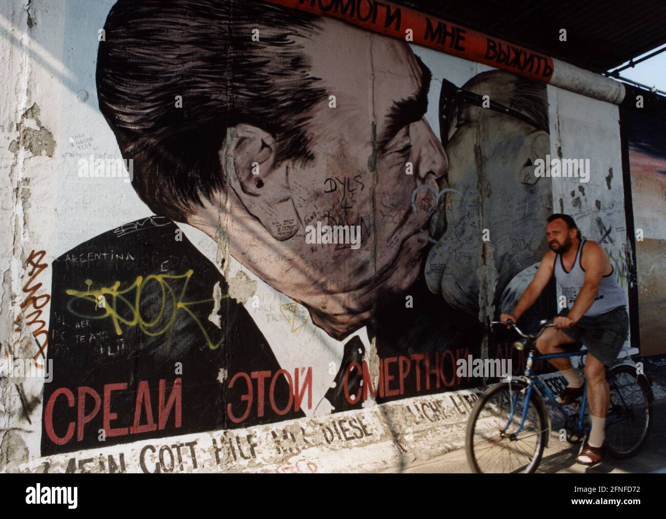 "Un passer-by davanti alla rappresentazione di Dmitri Wrubel del bacio fraterno tra Leonid Brezhnev ed Erich Honecker su un frammento del Muro. Intitolato: 'Il mio Dio mi aiuta a sopravvivere a questo amore mortale'' parte della East Side Gallery. (foto non datata) [traduzione automatica]' Foto Stock