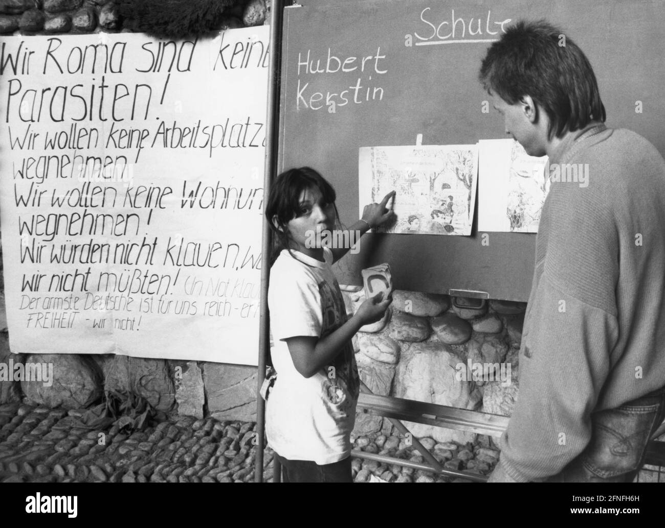 Una giovane Rom riceve lezioni di tedesco, dietro di lei un poster di accettazione pubblicitaria. Temendo la deportazione nella zona di guerra della Jugoslavia, le famiglie si erano ritirate nell'area delle due cappelle commemorative sul terreno del campo di concentramento di Dachau, dove erano protette dall'asilo della chiesa. [traduzione automatizzata] Foto Stock