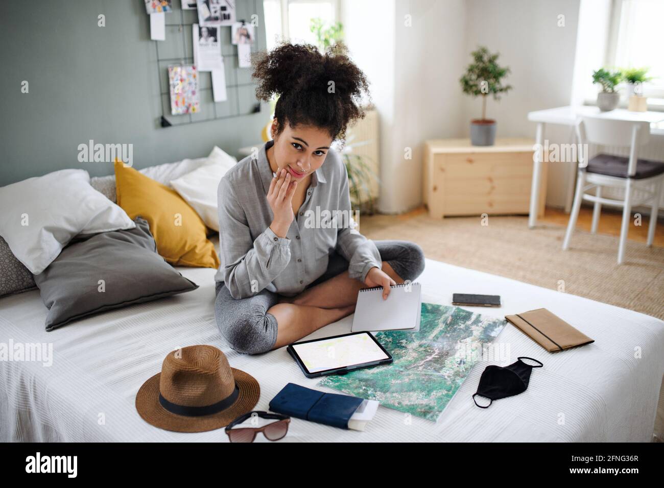 Giovane donna con tablet e mappa in interni a casa, pianificazione viaggio. Foto Stock