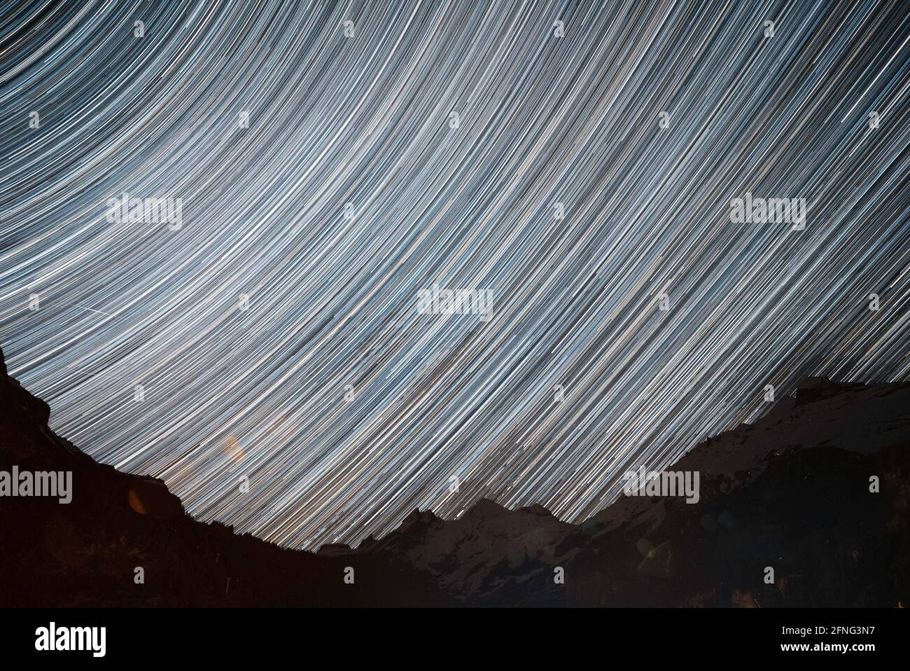 Splendidi sentieri stellari sopra le alte montagne alpine. I lunghi percorsi di esposizione si snodano attraverso il cielo mentre le stelle si muovono durante la notte Foto Stock