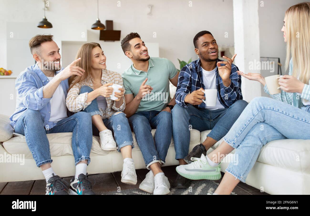 Gruppo di felici amici millenari che bevono il tè, che parlano, che si divertono insieme a casa Foto Stock