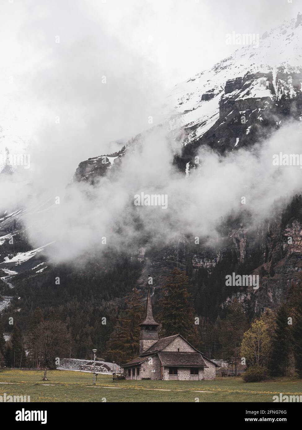 Bella vecchia chiesa rustica alpina e montagne innevate. La chiesa si trova nel villaggio alpino di kandersteg in Svizzera. Foto Stock