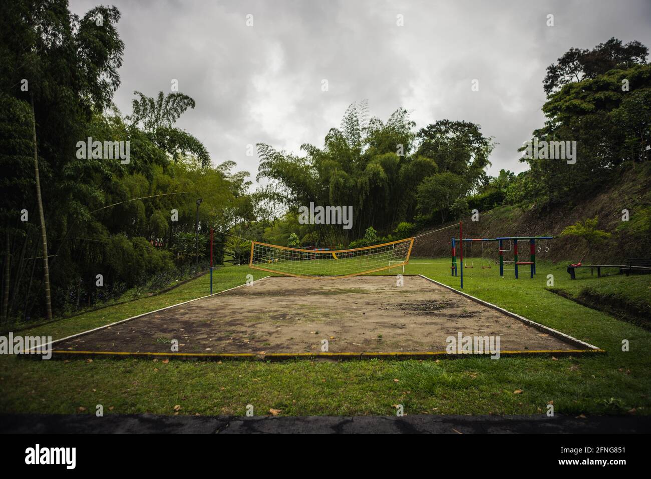 Ampio campo sportivo con campo da pallavolo e parco giochi Su terreno erboso lussureggiante in Colombia Foto Stock