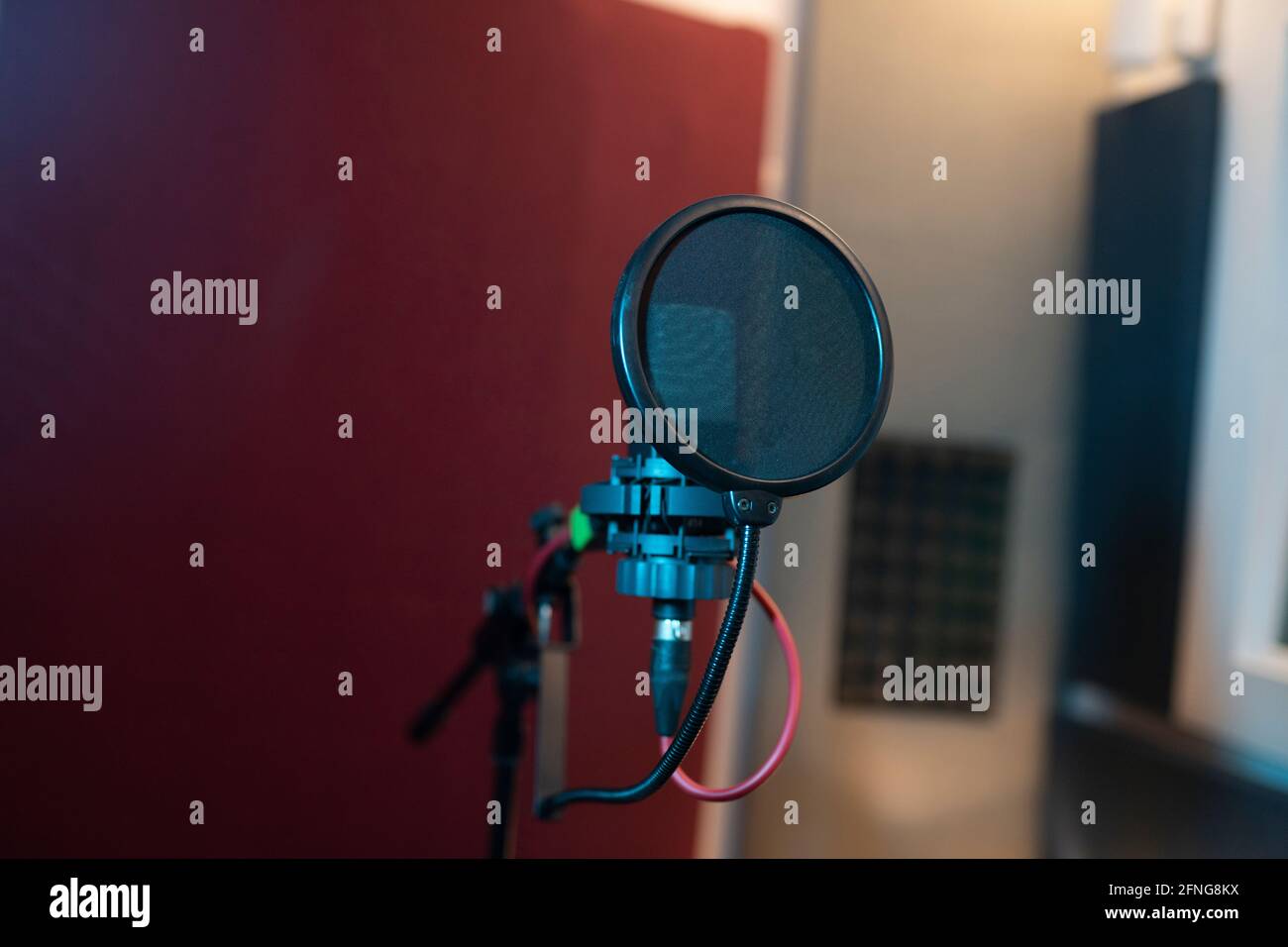 Filtro pop e microfono dinamico moderno con fili vuoti studio audio su sfondo sfocato Foto Stock