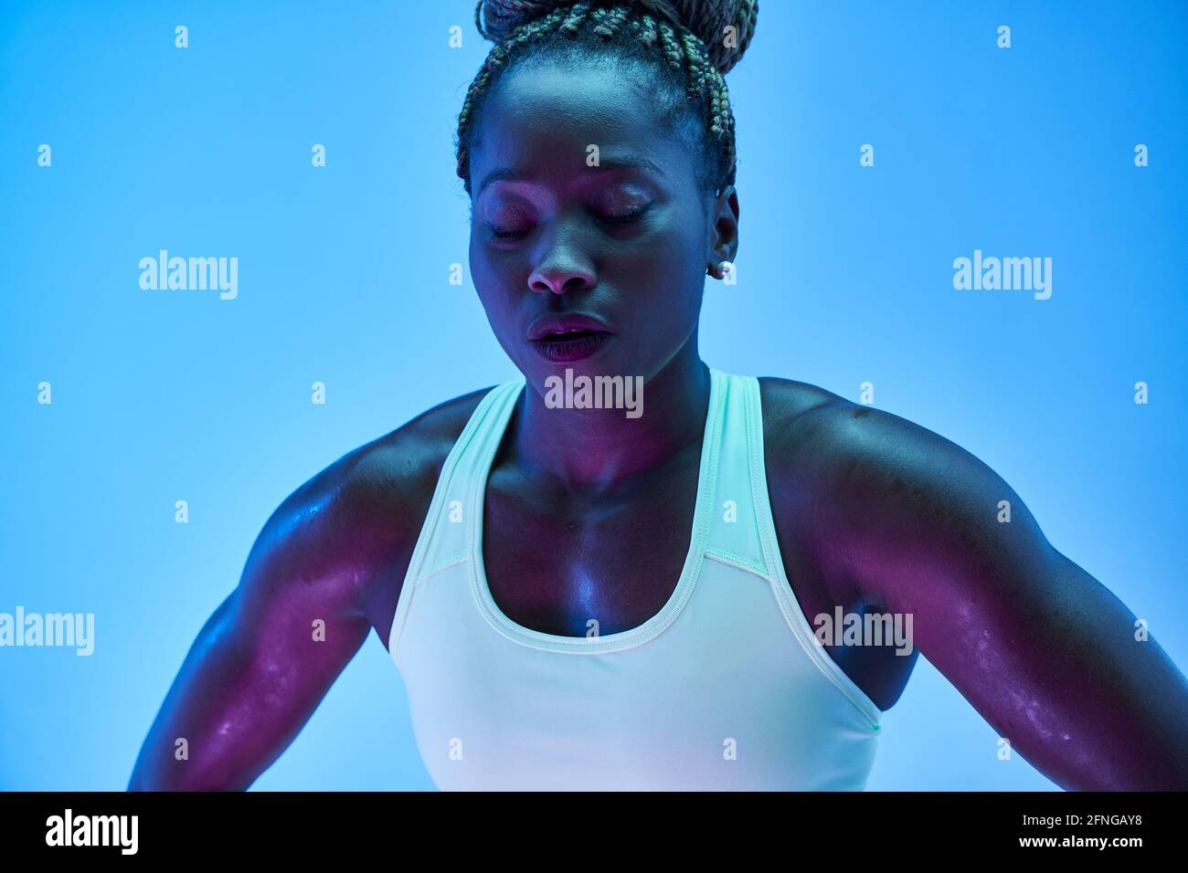 Giovane sportivo afroamericano con trecce afroamericane in panda e occhi chiusi su sfondo blu Foto Stock