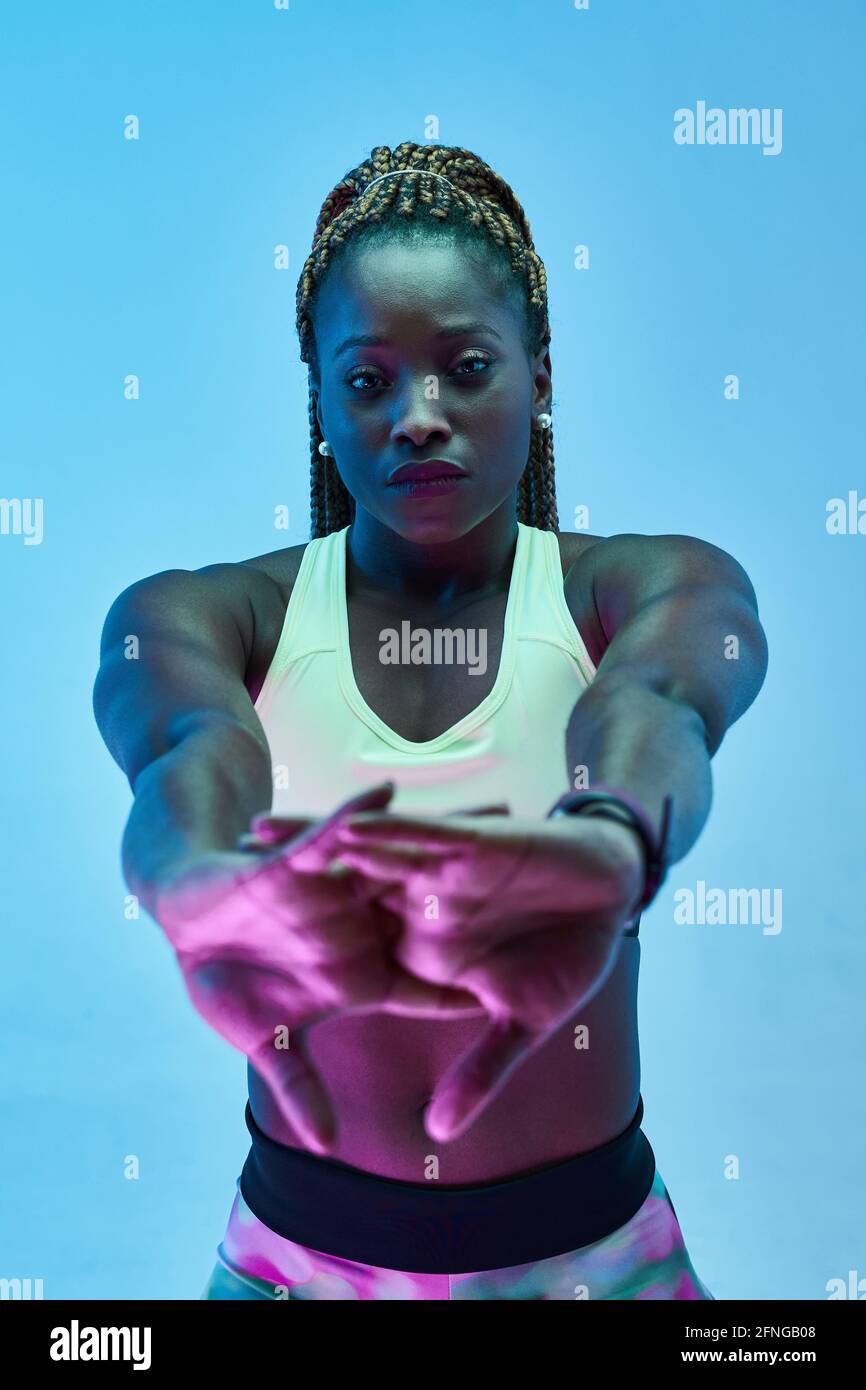 Giovane atleta muscolosa afro-americana in abbigliamento sportivo con  chiusura a strappo mani che si allenano mentre si guarda la fotocamera su  sfondo blu Foto stock - Alamy