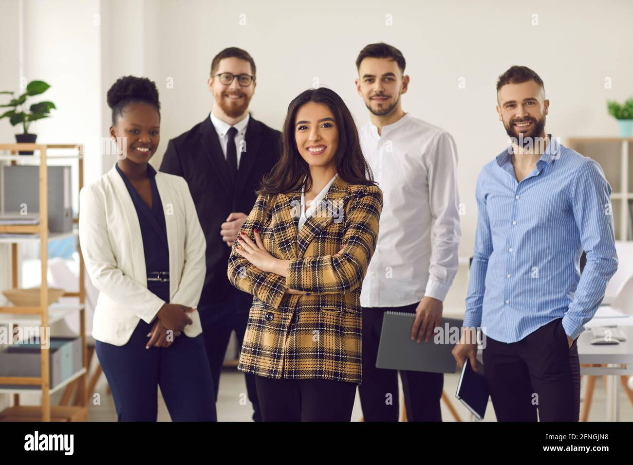 Donna d'affari sorridente con un gruppo di affari di squadra diverso in ufficio Foto Stock