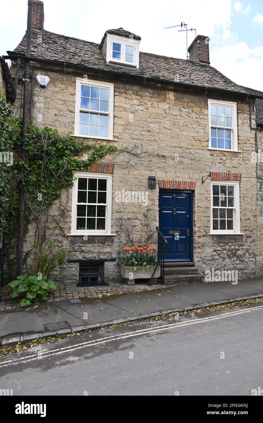 Una casa su Park Lane nel nord della città di Oxfordshire Di Woodstock con un trogolo di pietra riempito con tulipani dentro fiore all'esterno della porta anteriore Foto Stock