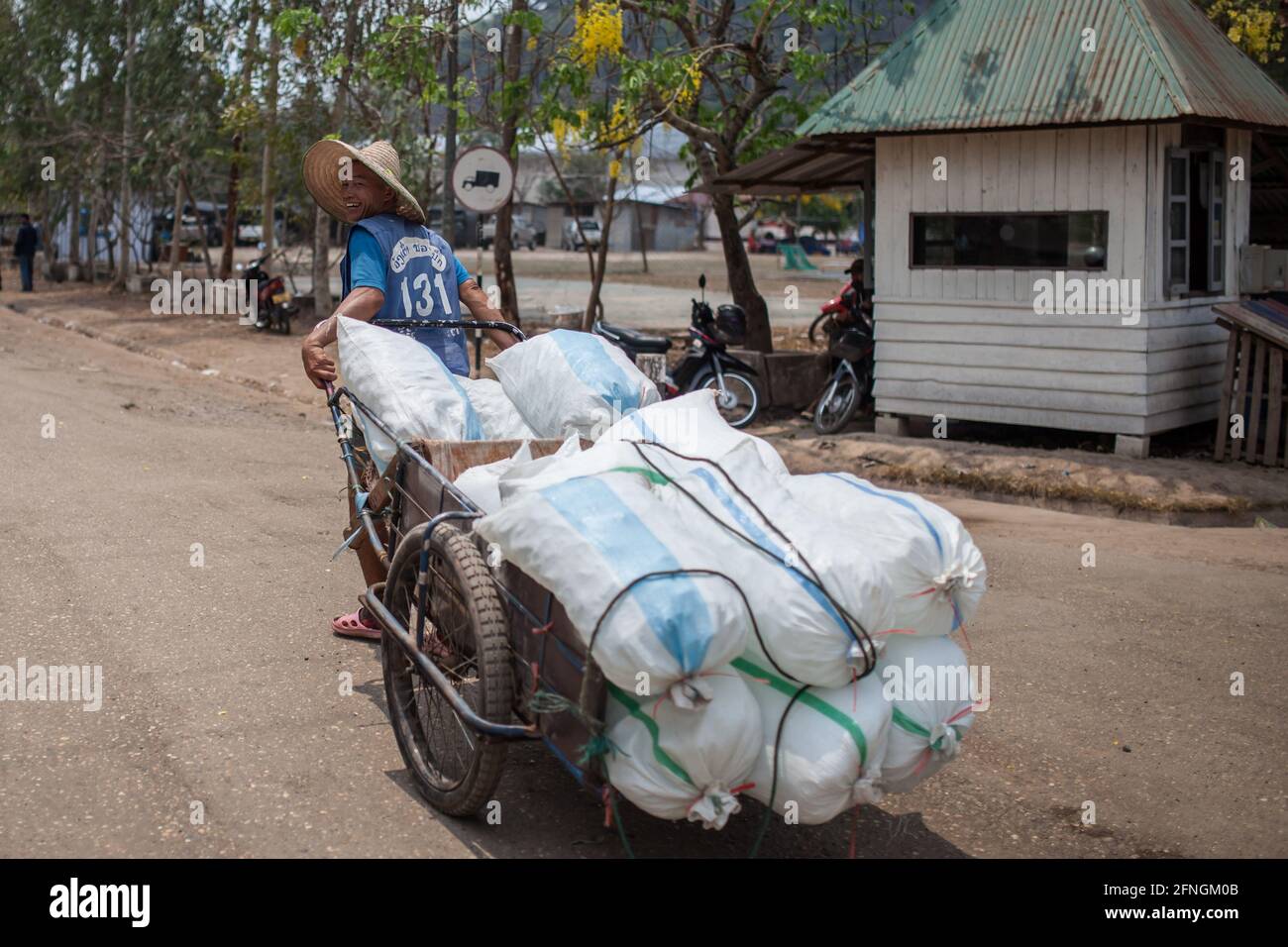 Vang Tao Border Crossing, Laos - 31 marzo 2013: Un uomo non identificato che tira un carrello completamente carico attraverso il valico di frontiera thailandese-lao. Foto Stock