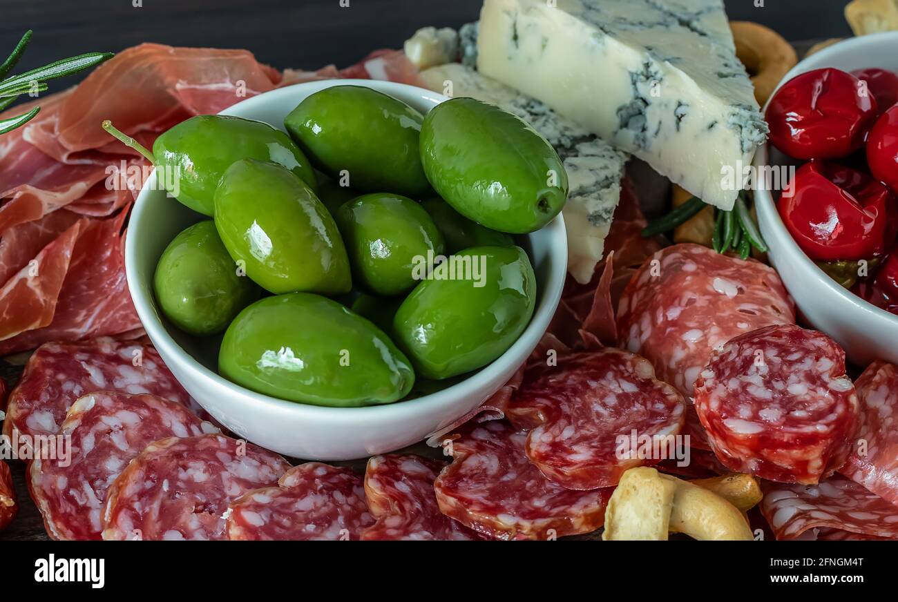 Salumi con salumi italiani, olive, peperoni, cracker, salsiccia, e prosciutto. Primo piano, messa a fuoco selettiva Foto Stock