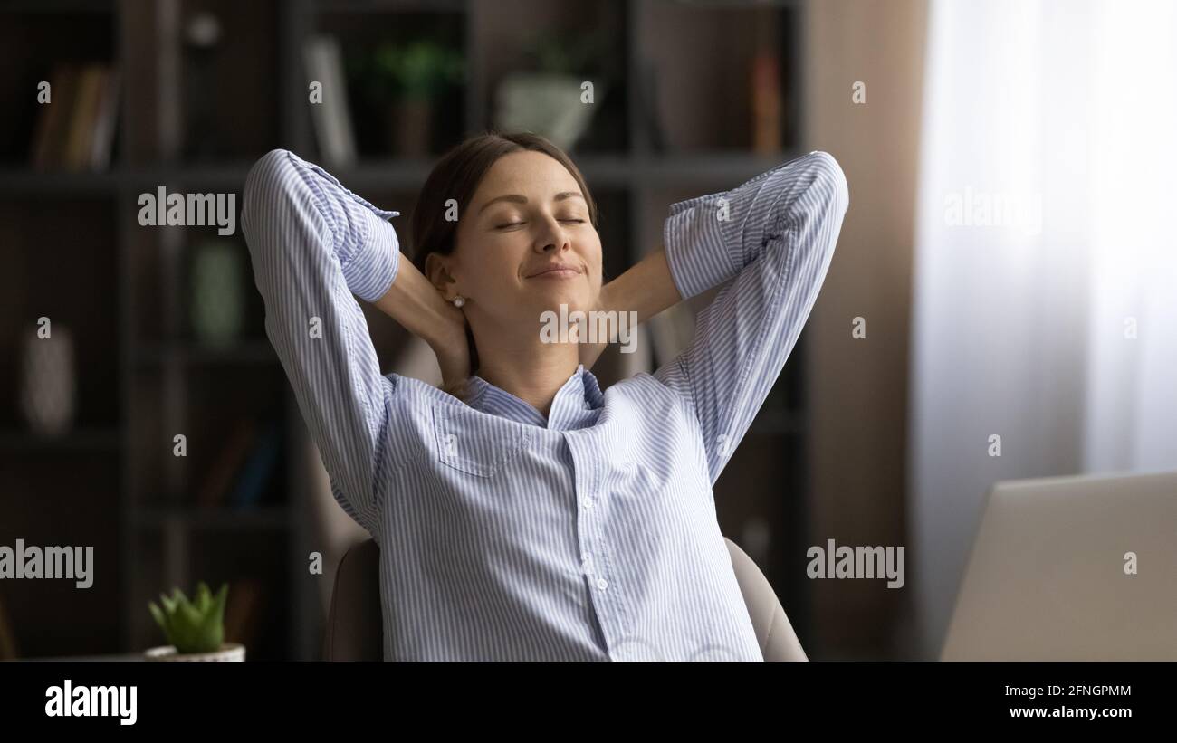 Tranquilla giovane donna rilassarsi alla scrivania prendere pausa nel lavoro Foto Stock