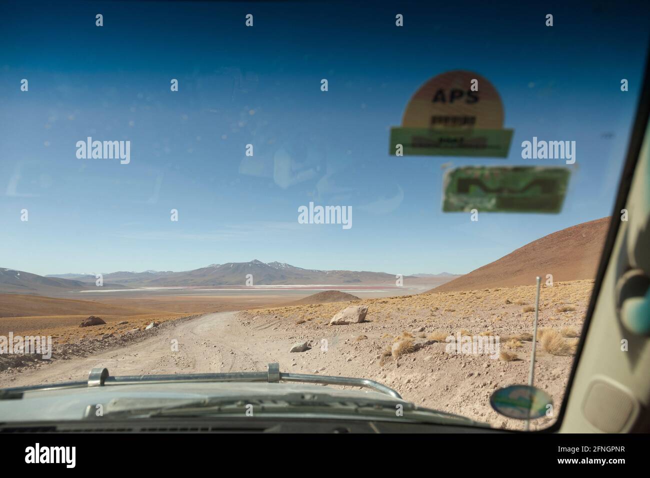 Visto dal sedile del passeggero anteriore, un veicolo 4x4 guida lungo una pista desertica boliviana in un safari turistico terrestre Foto Stock