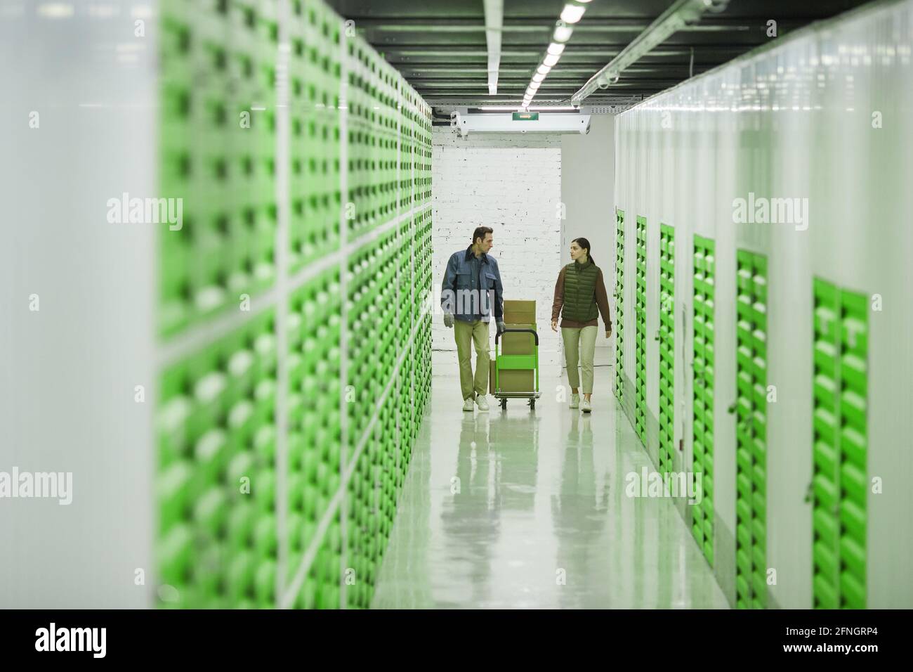 Due giovani che spingono insieme il carrello con le scatole e. spedizione in magazzino Foto Stock