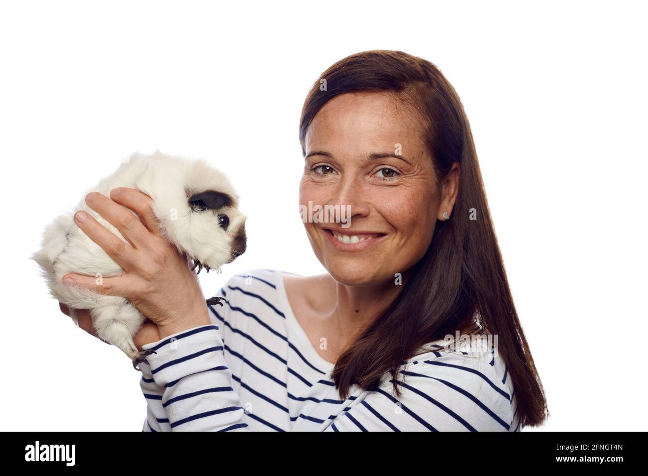 Donna amorevole felice che tiene in su il suo porcellino di cavia dell'animale domestico dentro le mani girandosi per guardare la fotocamera con un sorriso amichevole isolato su bianco Foto Stock