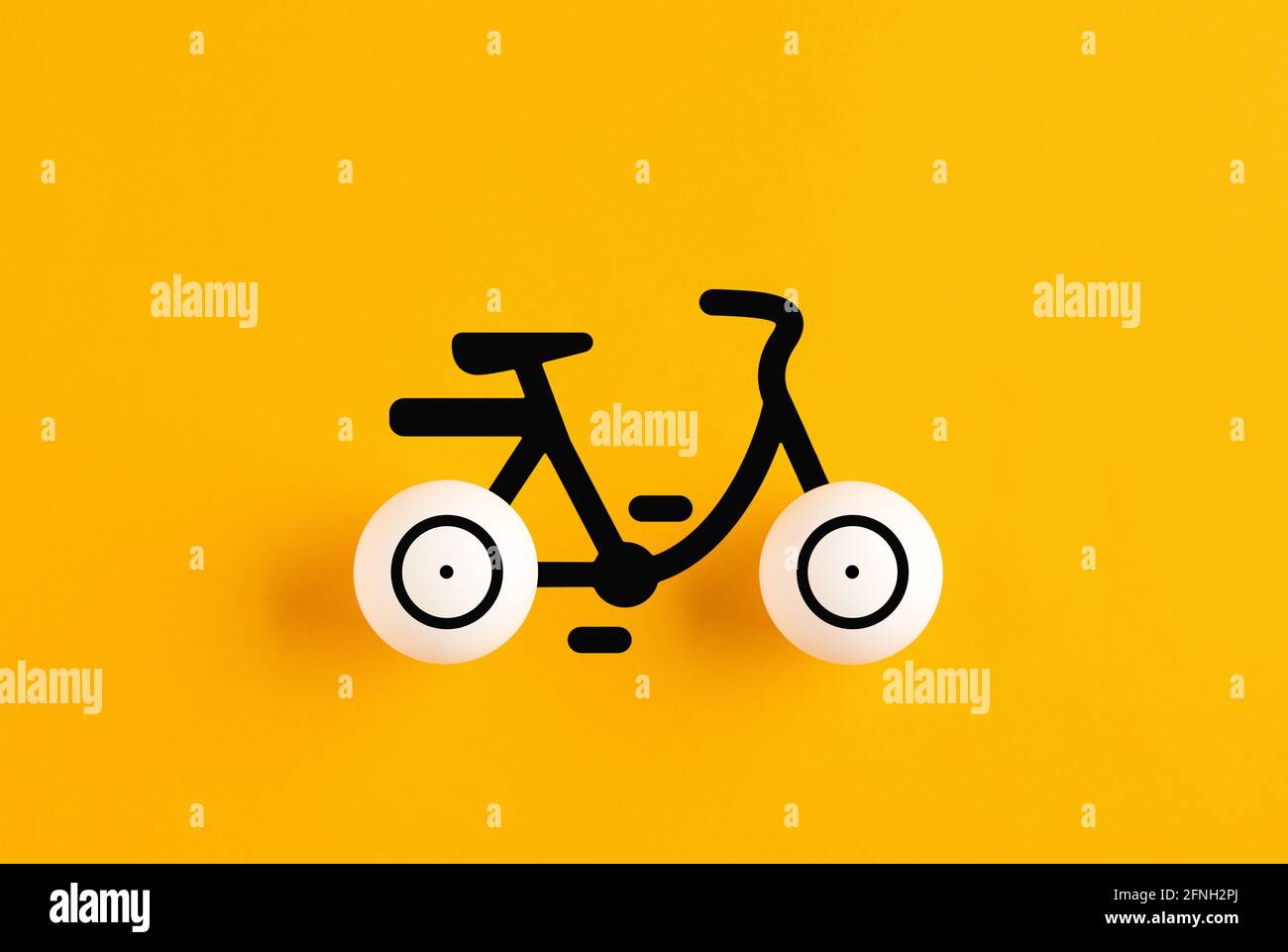 Icona della bicicletta composta da palle da ping-pong su sfondo giallo. Concetto di trasporto ambientale. Foto Stock