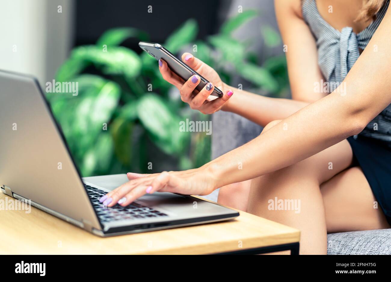 Donna d'affari impegnata che usa il telefono e il computer portatile per lavorare. Lavoratrice, multitasking ed elegante giovane donna in sala o in caffetteria. Foto Stock