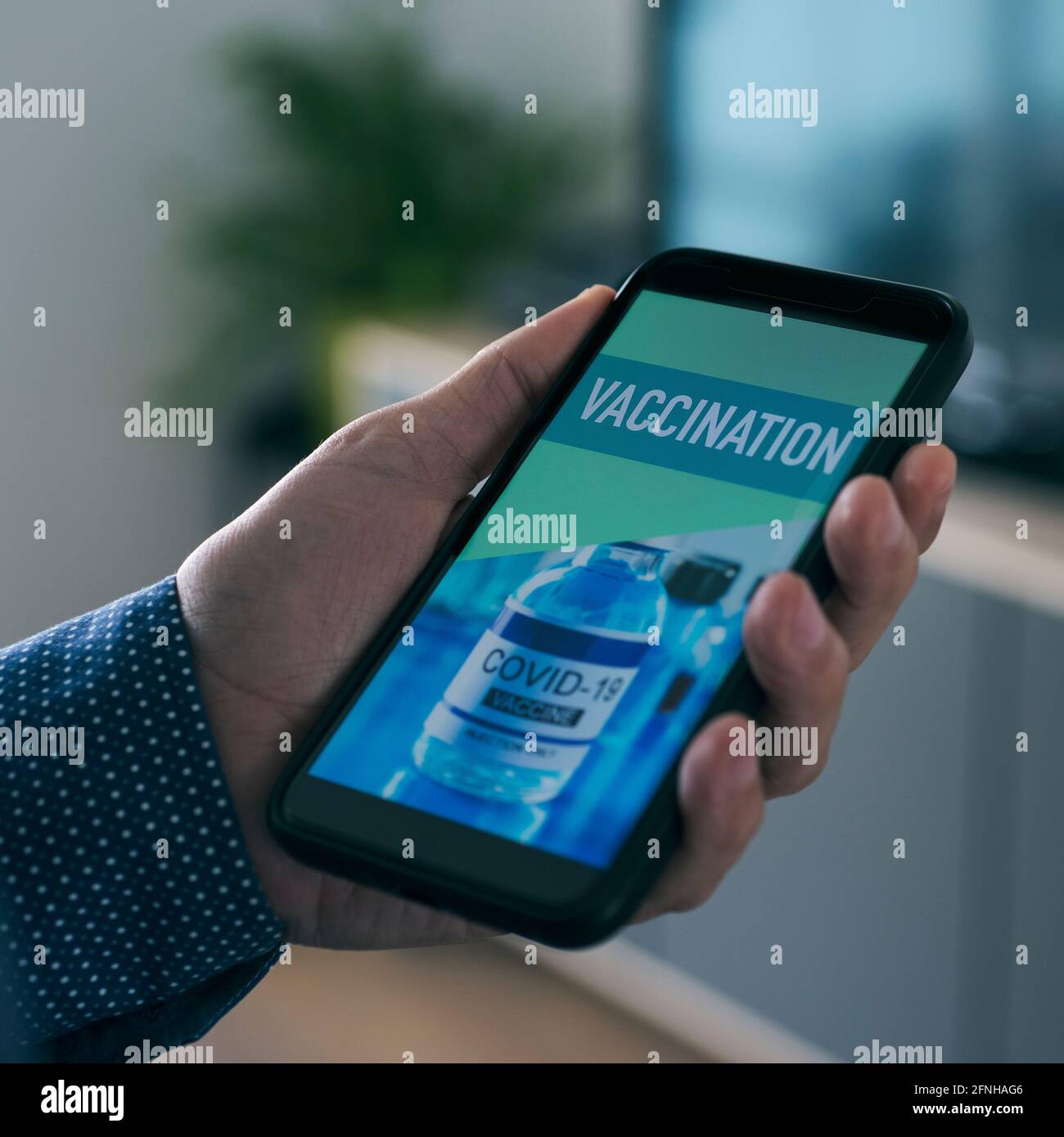 closeup di un giovane uomo caucasico, nel suo salotto, guardando il suo smartphone, che legge il testo vaccinazione nel suo schermo, in un'applicazione simulata a. Foto Stock