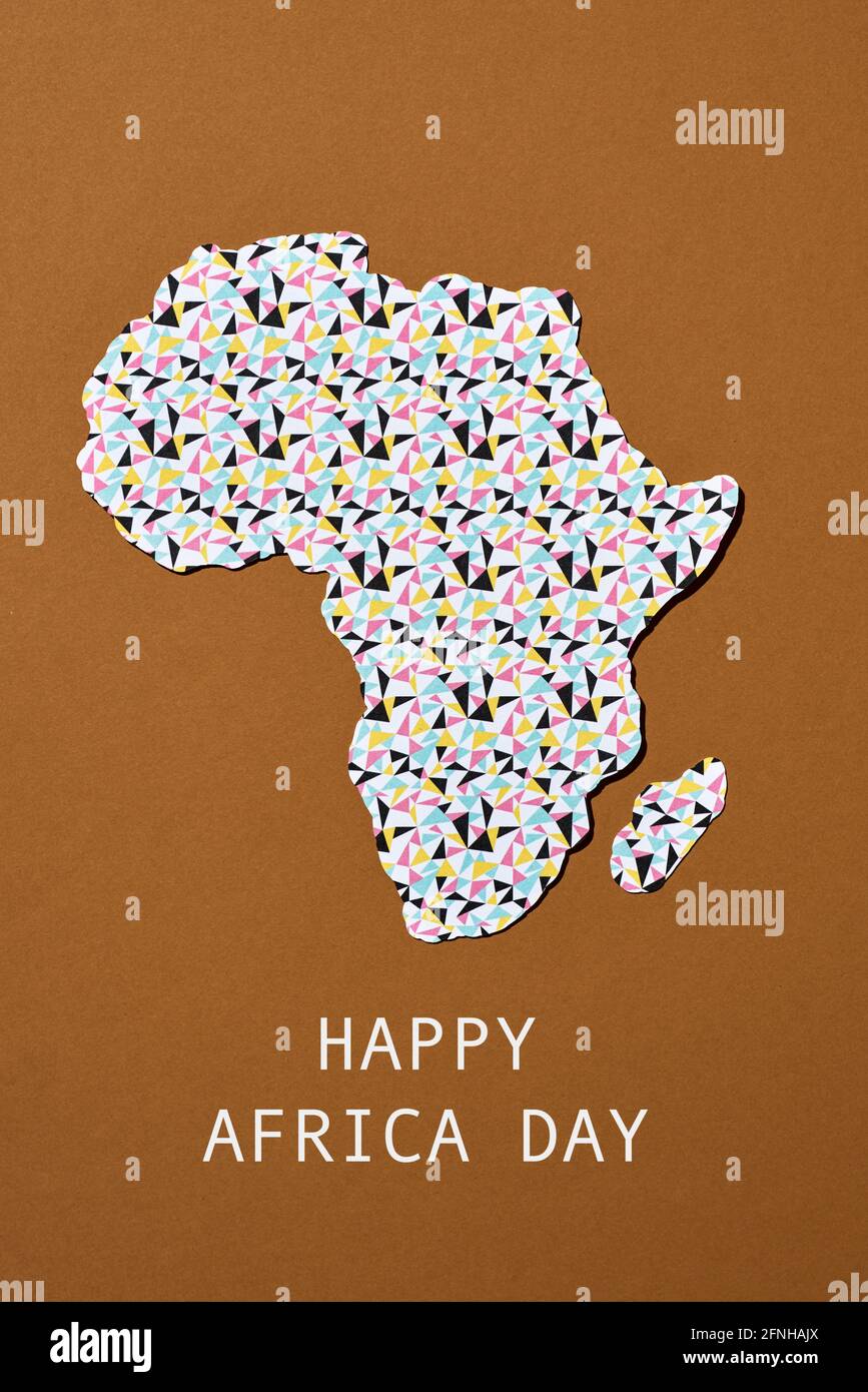 la silhouette dell'africa ritagliata da una carta modellata, e il testo happy africa giorno su uno sfondo marrone Foto Stock