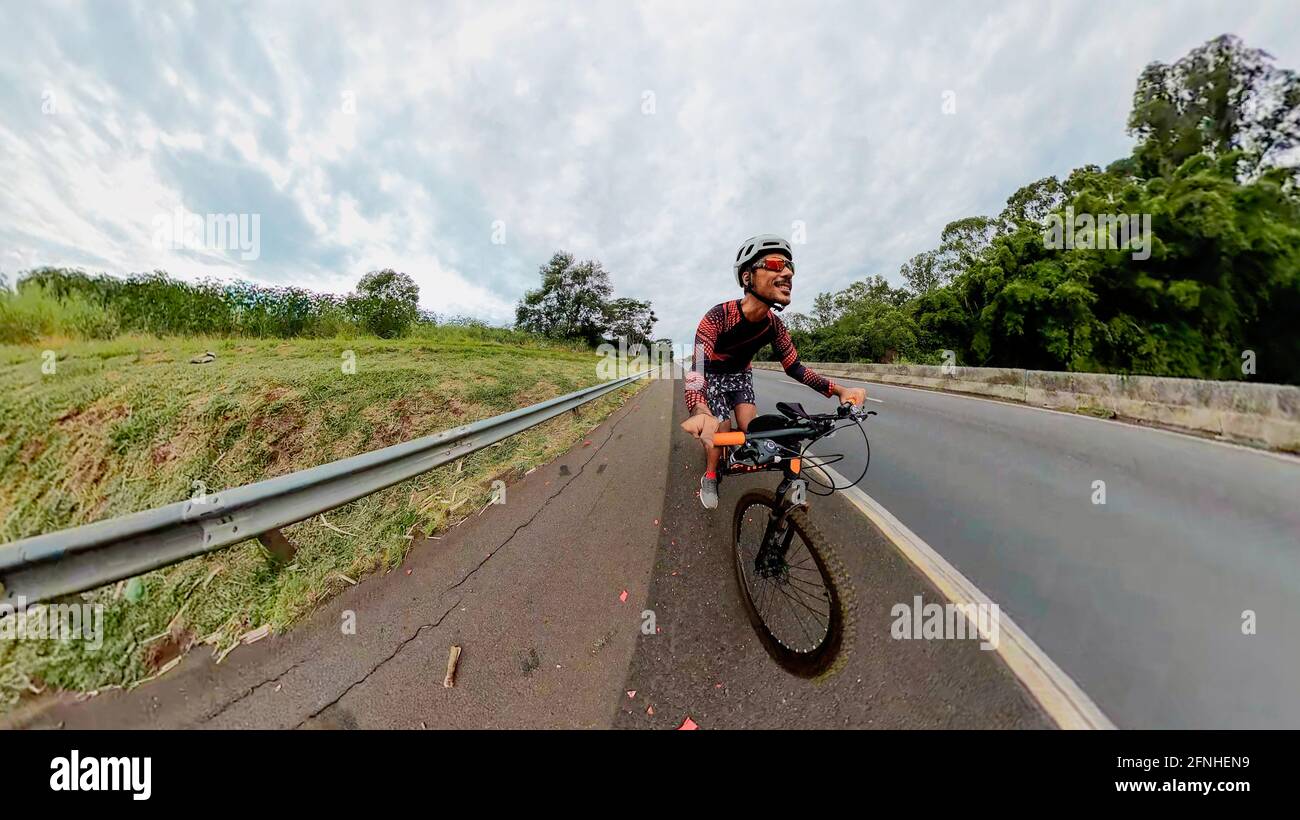 Uomo nero con casco e occhiali che cavalcano una bicicletta sulla strada. Foto Stock