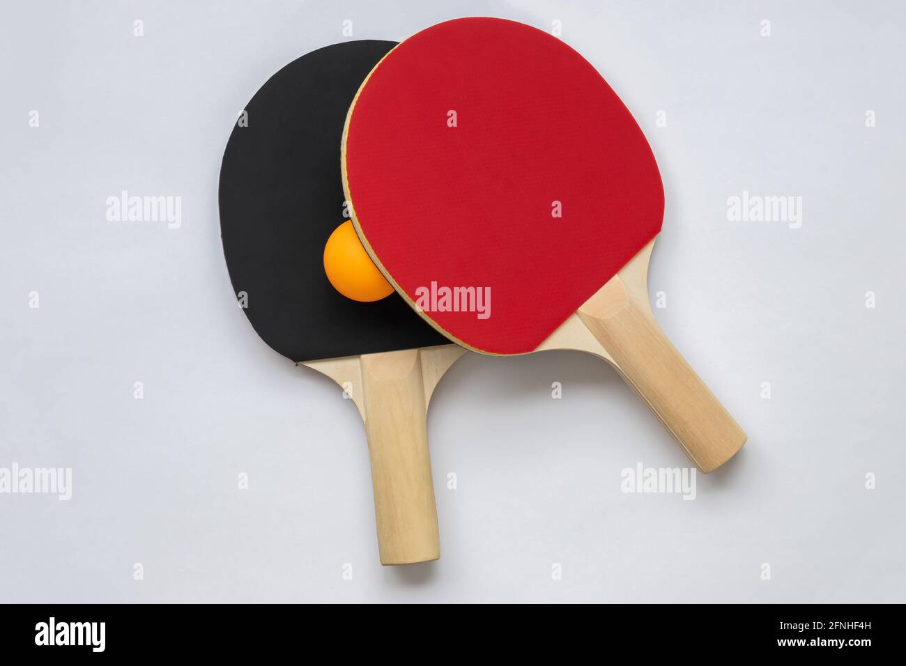 Racchetta da ping pong su sfondo bianco, con palla da ping pong arancione. Foto Stock