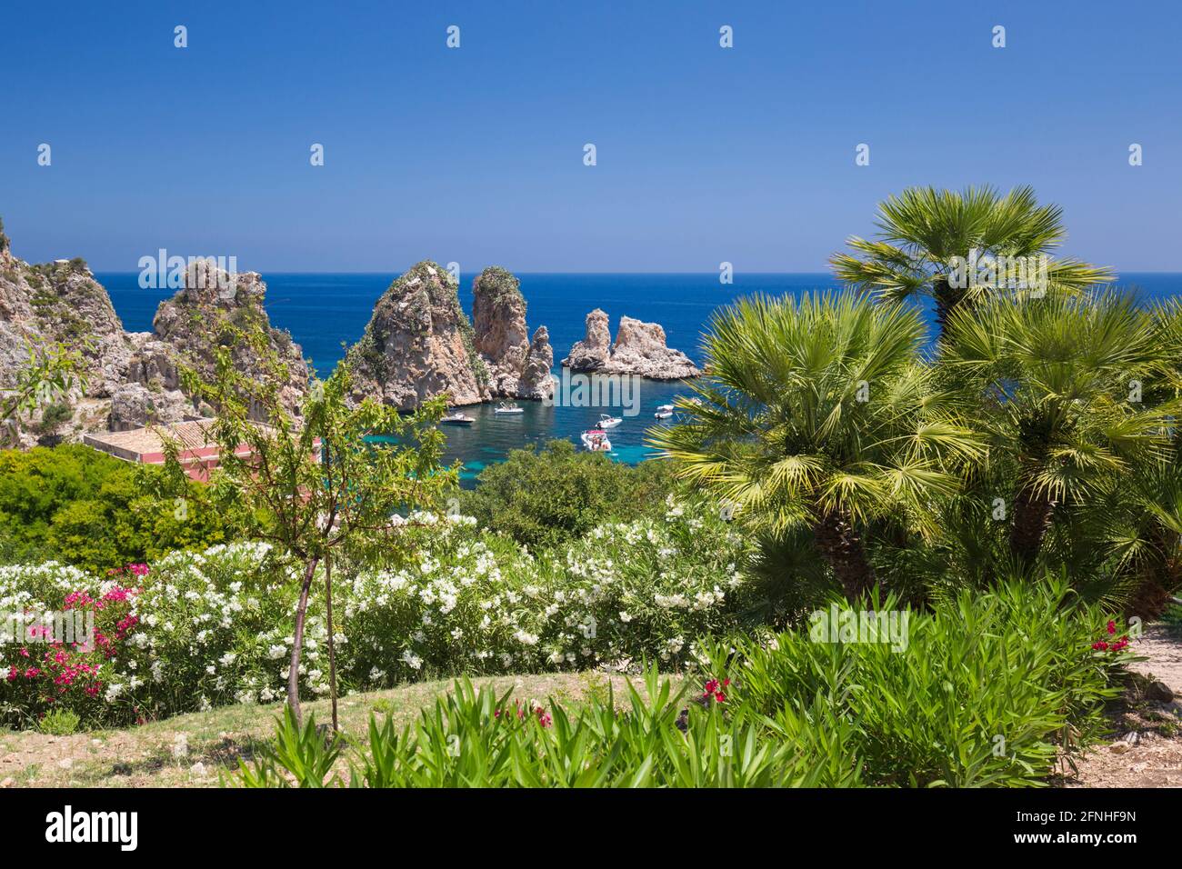 Scopello, Trapani, Sicilia, Italia. Vista su una baia rocciosa fino ai Faraglioni, una serie di pile nel Golfo di Castellammare al largo della Tonnara di Scopello. Foto Stock