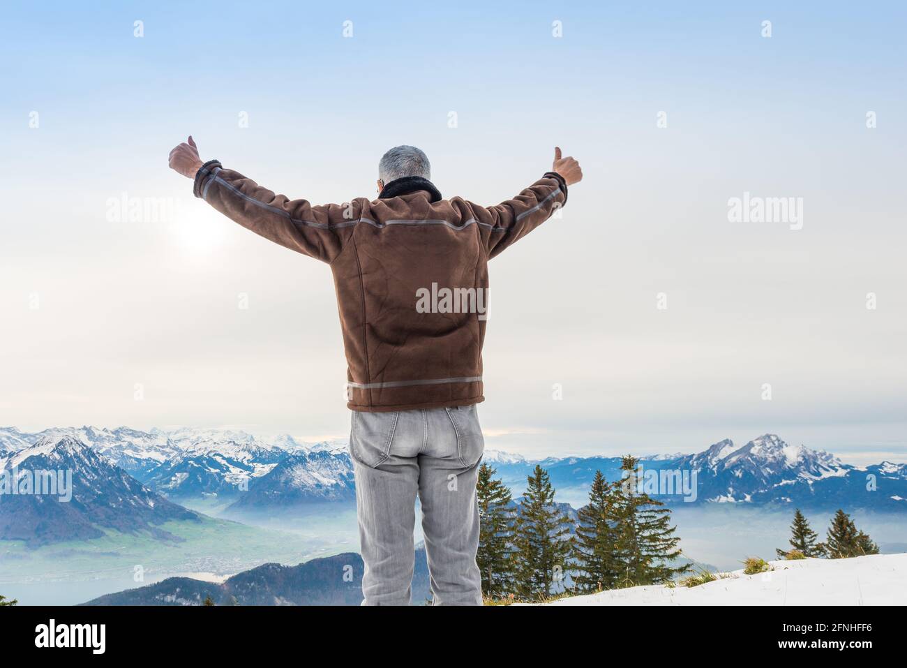 Un uomo anziano con capelli grigi. Apri le braccia con un gesto gioioso. Paesaggio di montagna. Svizzera. Riga. Foto Stock