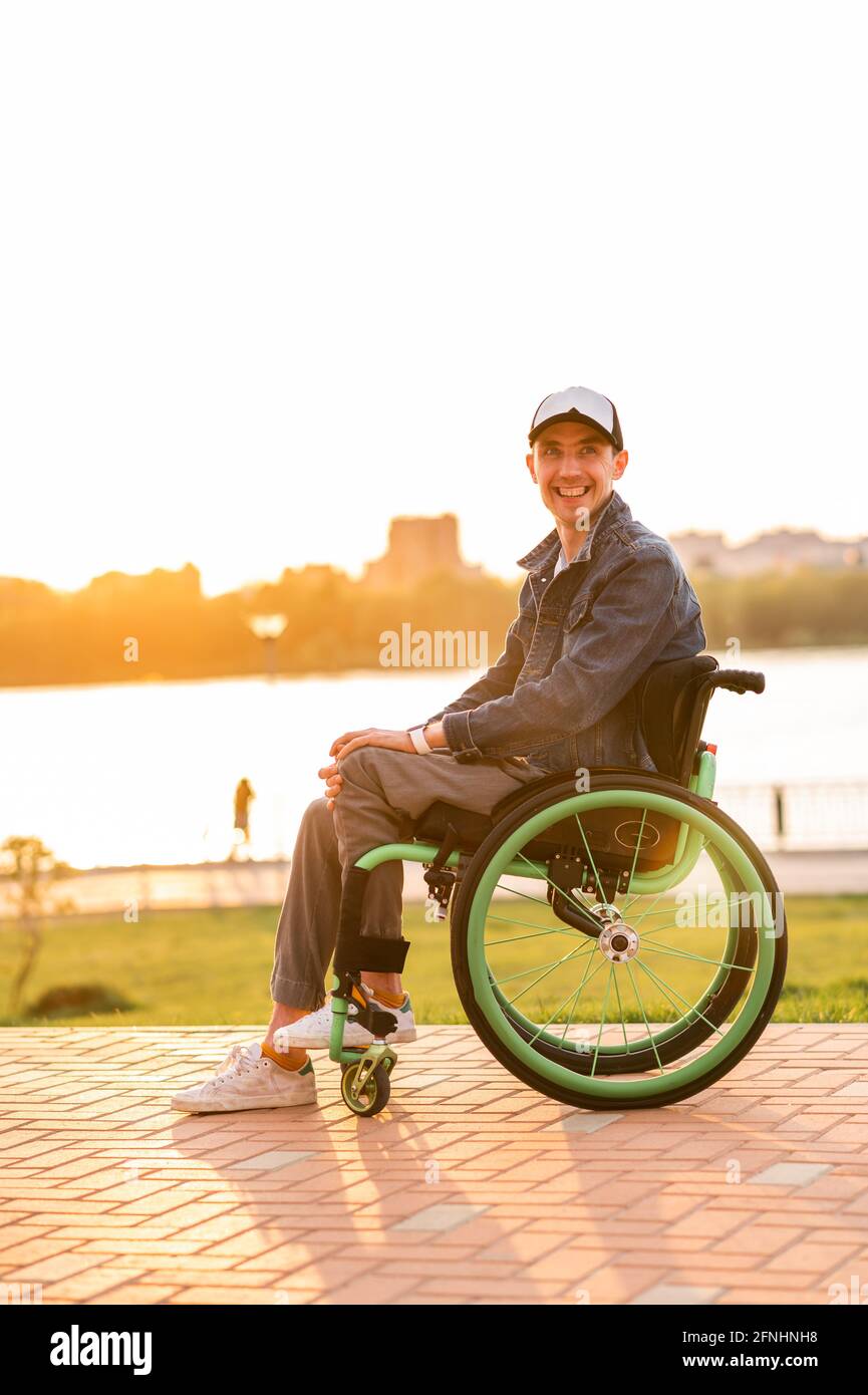 giovane ragazzo disabile in sedia a rotelle. Persone disabili in sedia a rotelle per passeggiate al tramonto Foto Stock