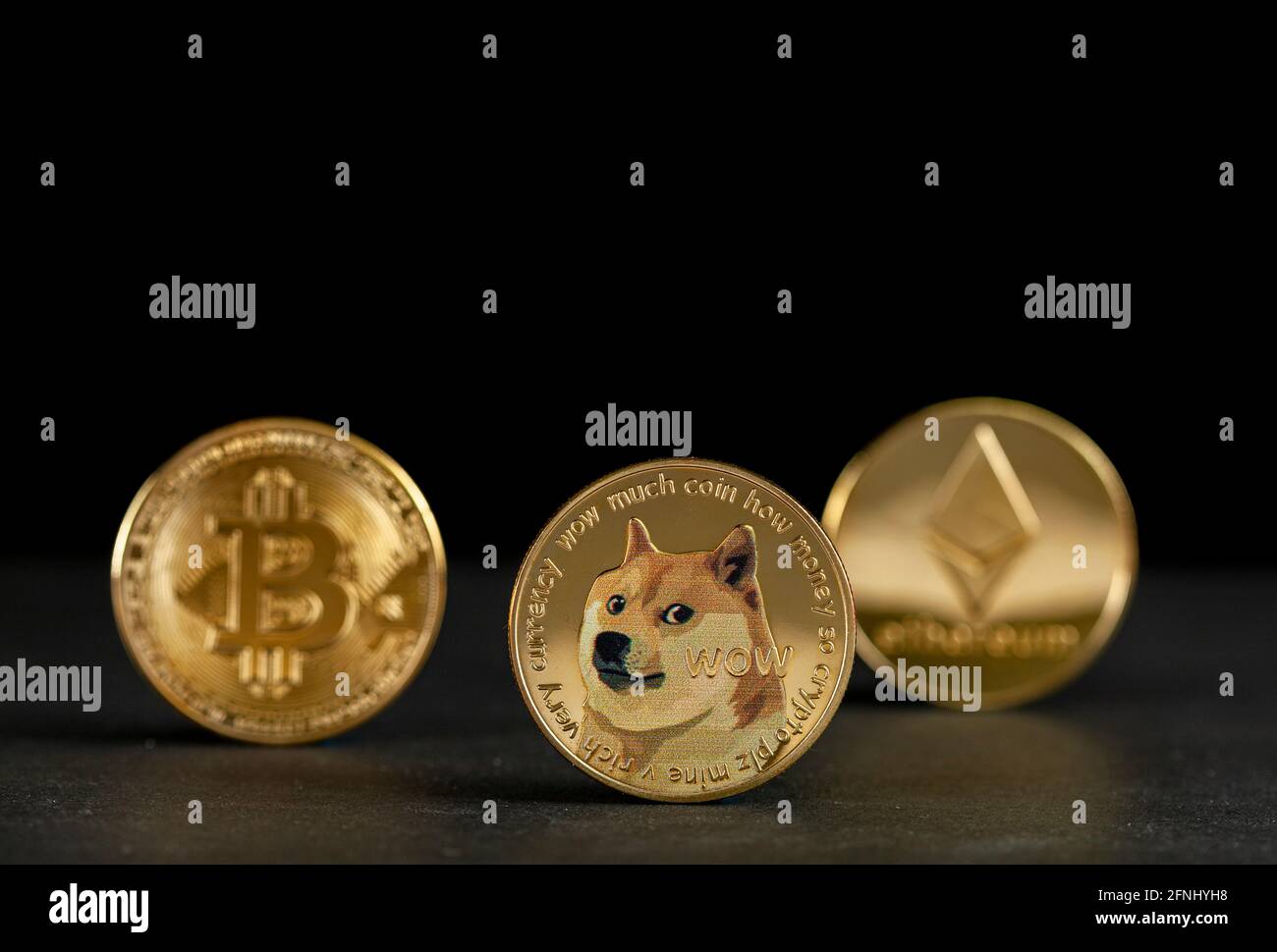 I tipi simbolici di criptovaluta rappresentati come monete lucide sono allineati su sfondo scuro. Tra loro il dogecoin che ha cominciato come scherzo è currentl Foto Stock