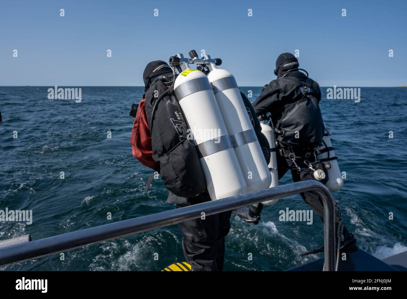 17 aprile 2021 - Hamburgsund, Svezia: Un subacqueo entra in acqua. Entra uno stride gigante. Serbatoio a due set. Oceano e cielo blu sullo sfondo Foto Stock