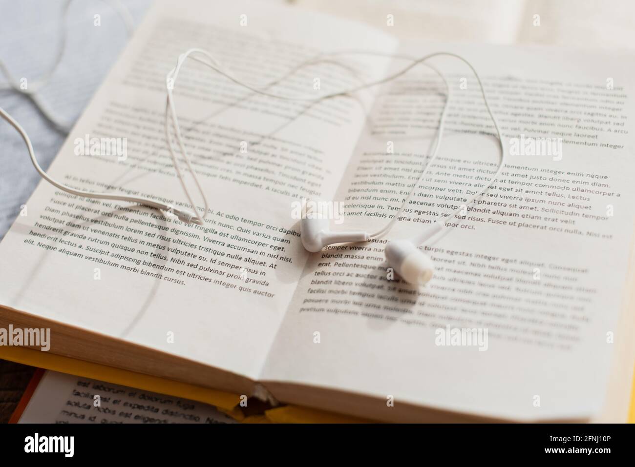 primo piano di auricolari bianchi su libri sfocati Foto Stock