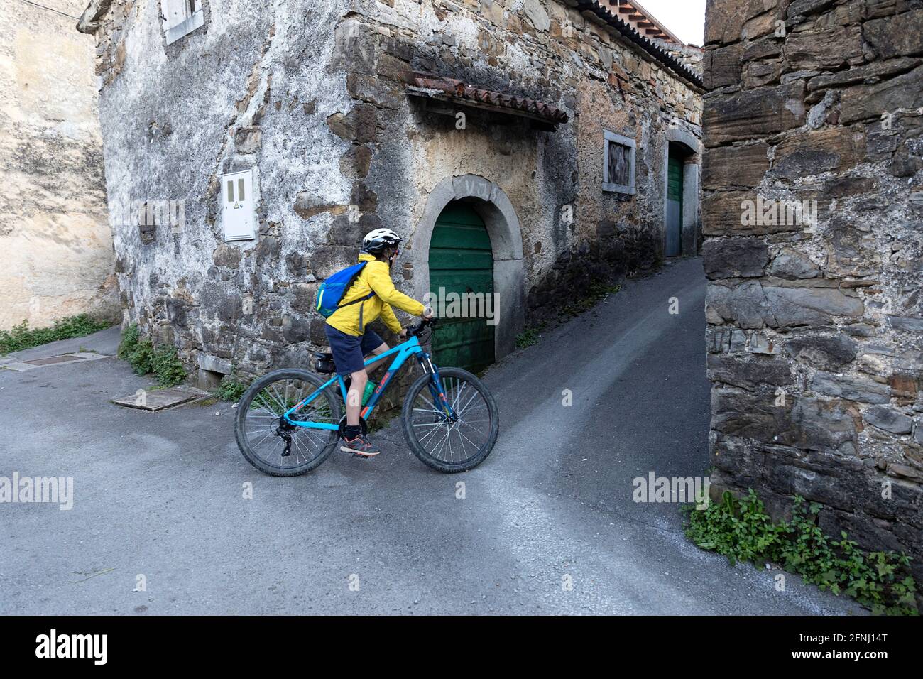 Pedalando nella stretta strada di Goce, piccolo villaggio nella valle di Vipava, campagna slovena, passando da rustiche case di pietra tradizionali, Foto Stock