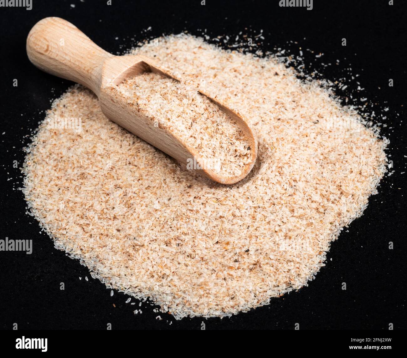 Piccola paletta di legno in buccia di Psyllium su piastra nera Foto Stock