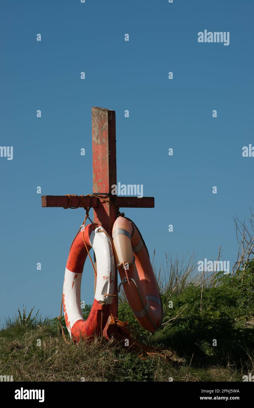 Immagine ravvicinata di due cinture di sicurezza con cordoncino fissato a un palo di legno tra le dune di sabbia costiere e contro un cielo blu vivido Foto Stock
