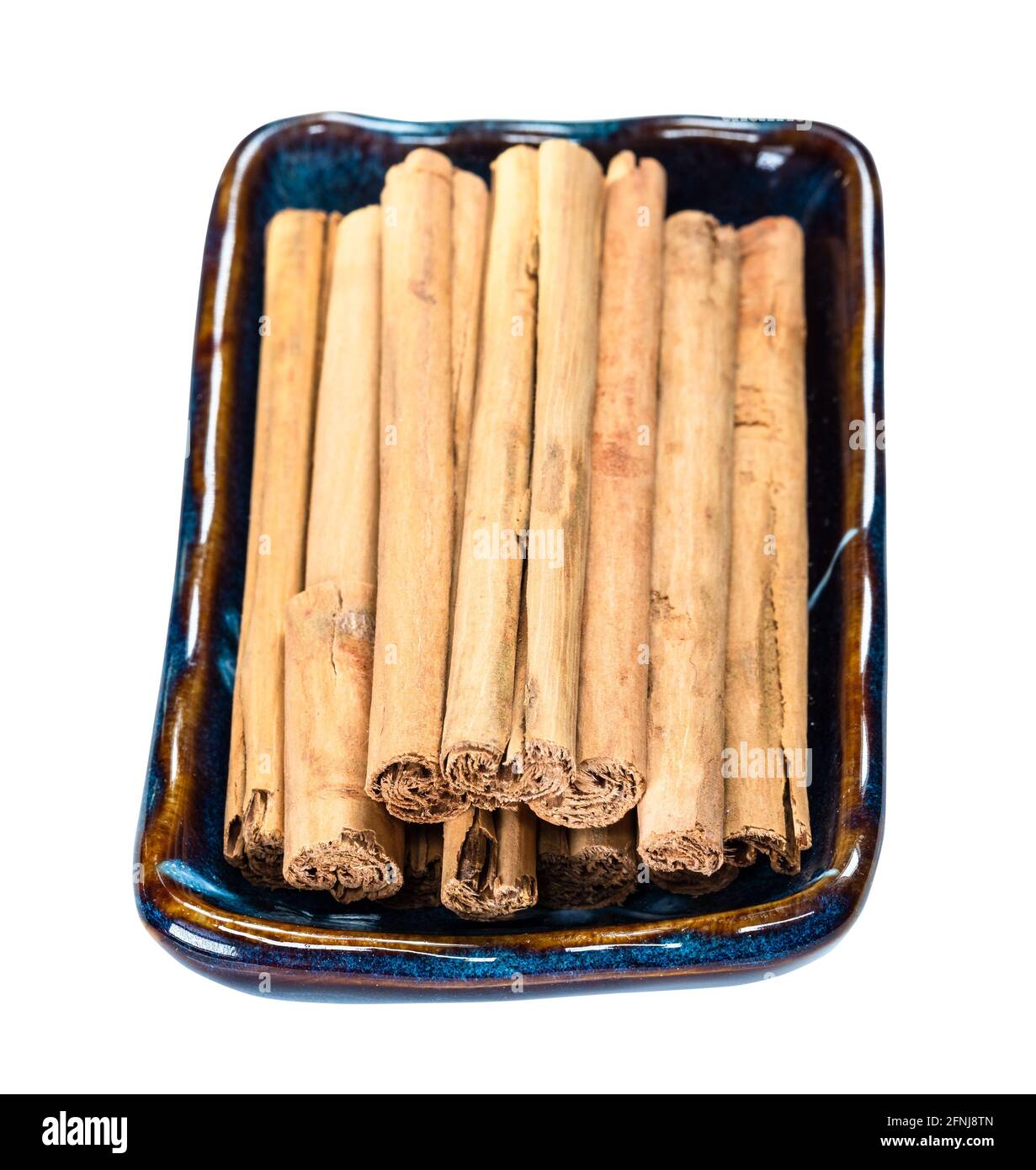 vista finale di quills di erba premiumin ceylon cannella in scodella in ceramica tagliata su sfondo bianco Foto Stock