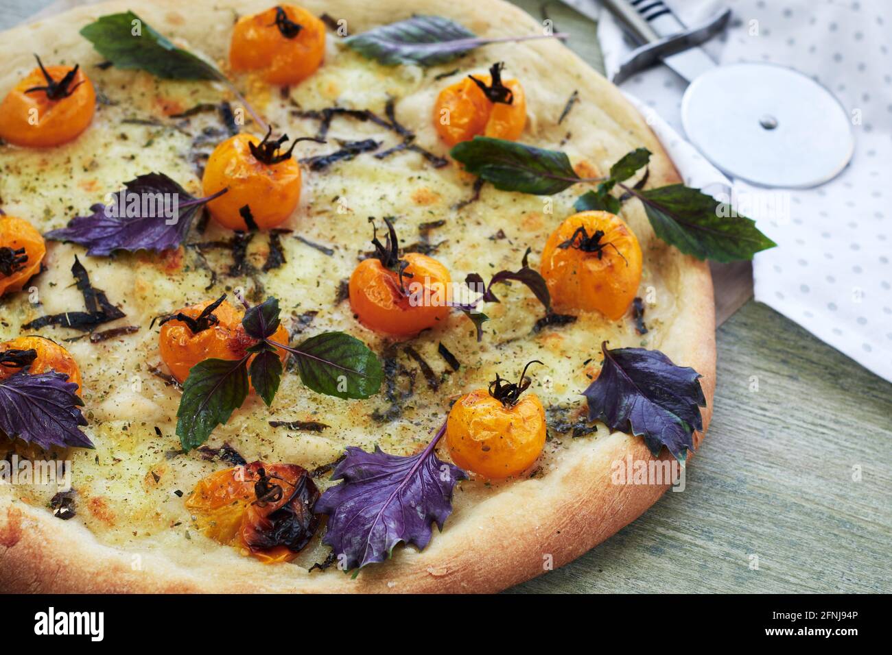 Pizza con pomodori ciliegini gialli, formaggio e basilico. Foto Stock