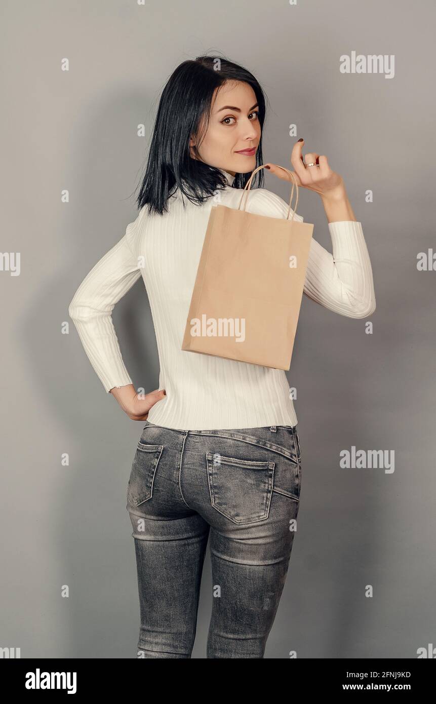 Donna bruna che tiene in mano una borsa di carta per la spesa. Imballaggio ecologico. Foto Stock