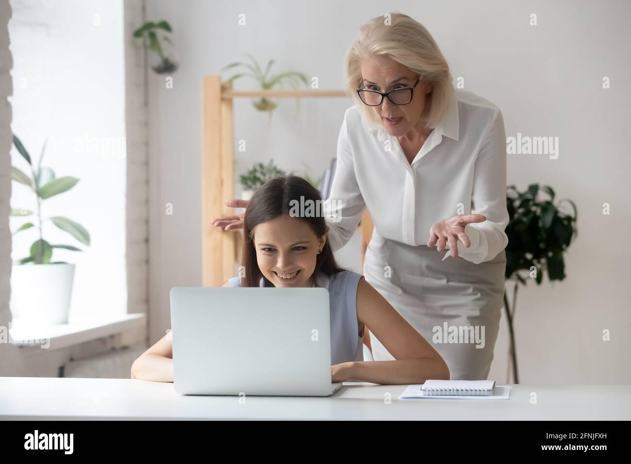 Donna d'affari anziana arrabbiata scioccata da una dipendente femminile non professionale Foto Stock