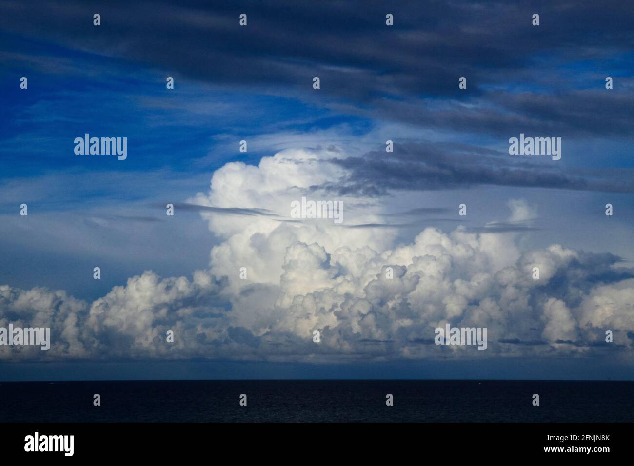Vista panoramica delle acque oceaniche linea orizzonte con drammatico cumulo temporale paesaggio nuvoloso in blu cielo sfondo. Foto Stock