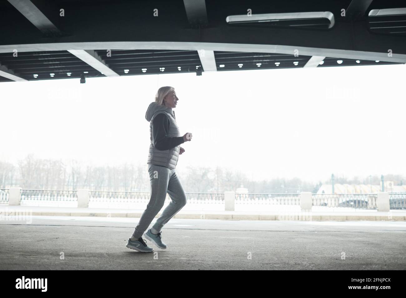 Donna anziana in forma grigia tuta da jogging da sola sotto bridge mentre  si allenano all'aperto Foto stock - Alamy