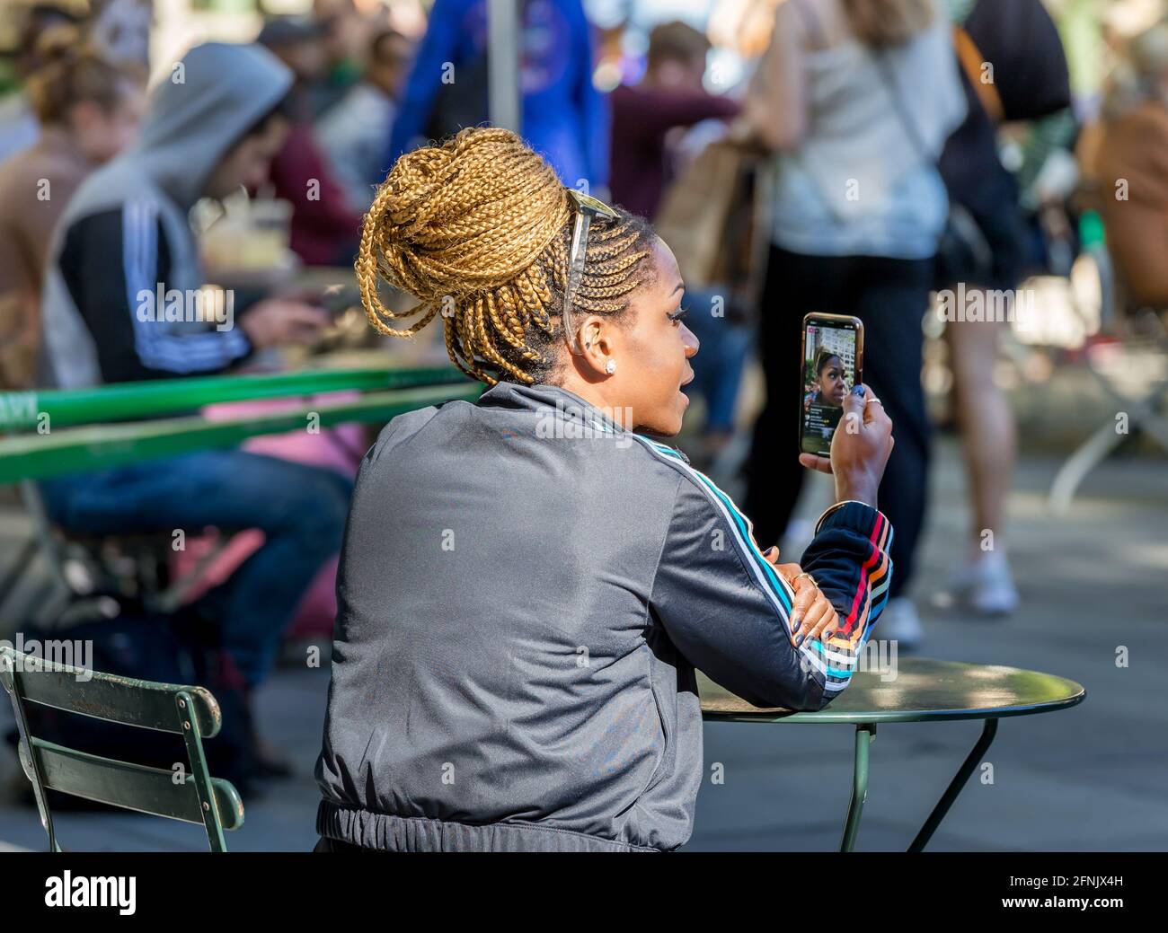 Donna afroamericana che ha video chat al telefono al parco di New York, USA Foto Stock