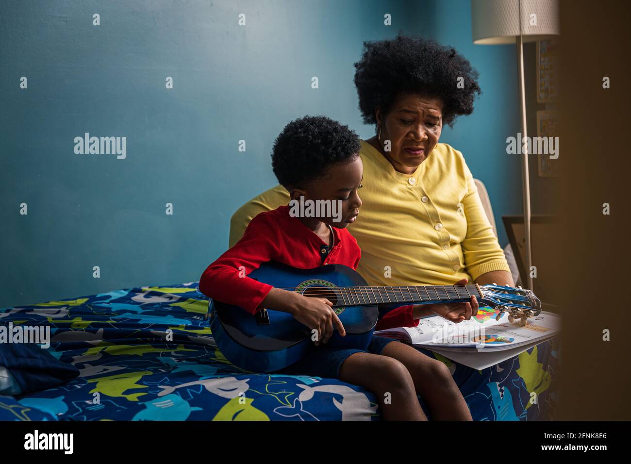 Nonna che guarda il nipote che pratica la chitarra a casa Foto Stock